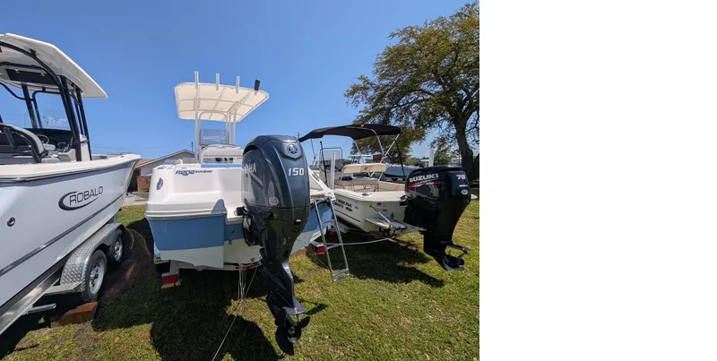 Slide: The Image of 2025 Robalo R202 Explorer boat with outboard motor, parked on grass. - 3