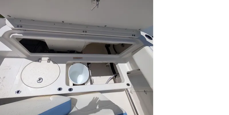 Slide: The Image of 2025 Robalo R202 Explorer boat storage compartment with open lid and bucket inside. - 12