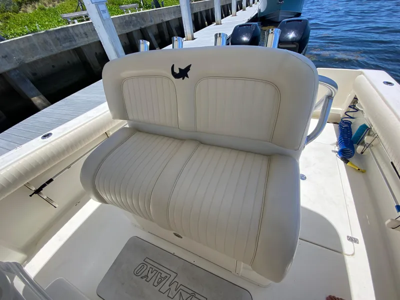 Slide: The Image of 2014 Mako 284 CC boat interior with cushioned seating and dockside view. - 15