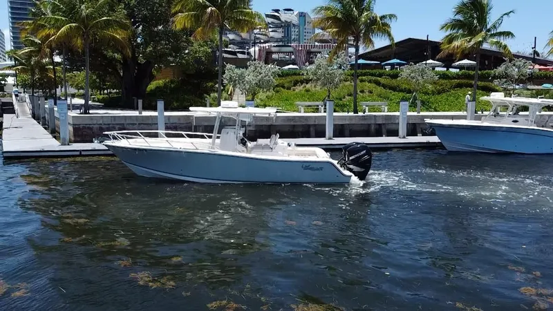 Slide: The Image of 2014 Mako 284 CC boat cruising near a tropical dock with palm trees. - 4