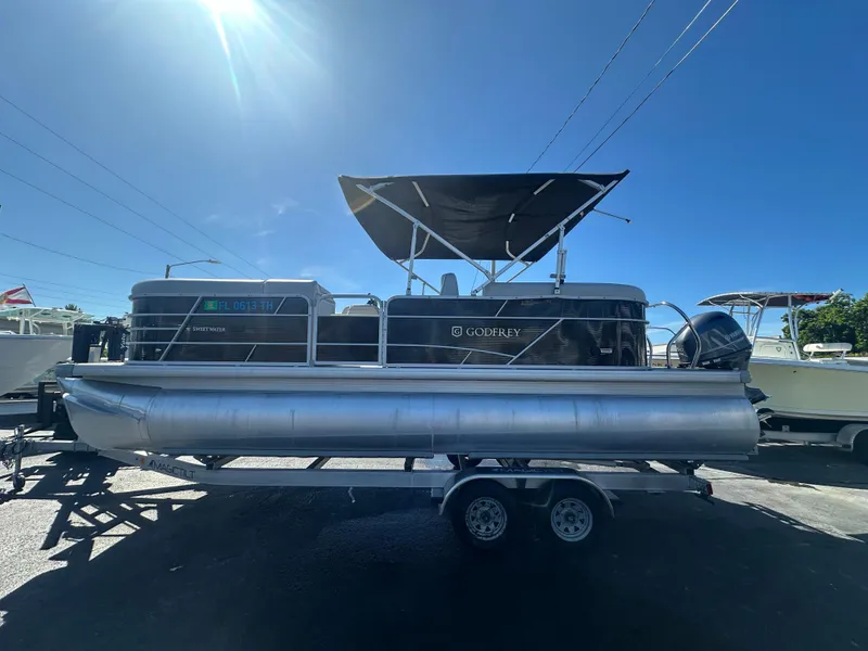 Slide: The Image of 2022 Godfrey Sweetwater 2286 FS pontoon boat on trailer under clear blue sky. - 1