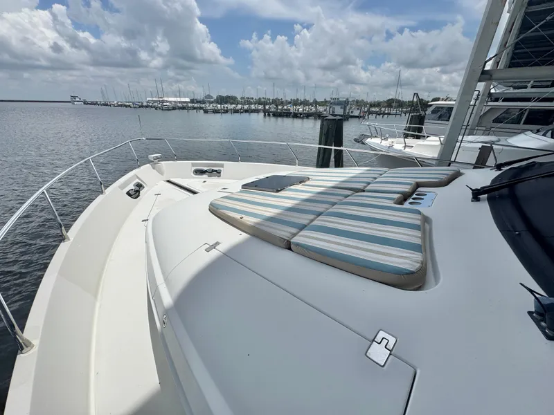 Slide: The Image of 2006 Marquis 65 yacht with striped sun pads, docked at a marina under cloudy skies. - 16