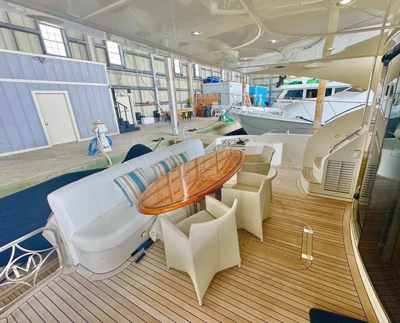 Slide: The Image of Luxurious 2006 Marquis 65 yacht deck with elegant seating and wooden table in a marina setting. - 17