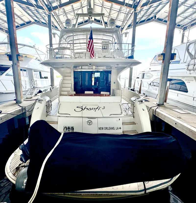 Slide: The Image of Luxury Marquis 65 yacht from 2006 docked, featuring an American flag and covered equipment. - 9