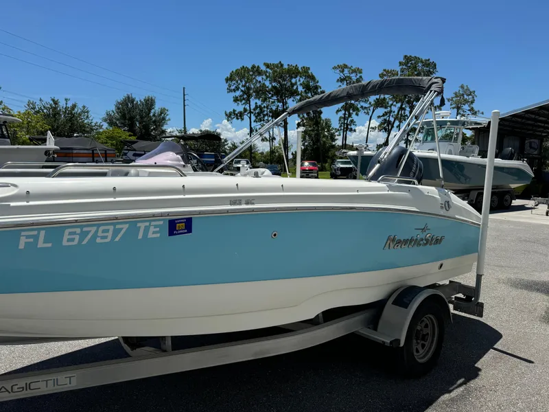 Slide: The Image of 2022 NauticStar 193SC boat on trailer, light blue and white, parked outdoors. - 4