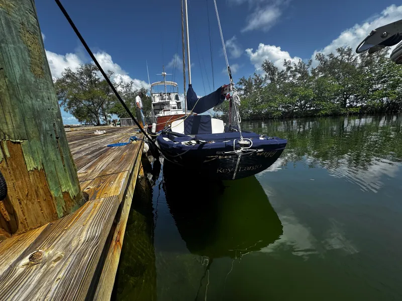 Slide: The Image of 1968 Sailboat 24 docked on calm water under a clear blue sky. - 12