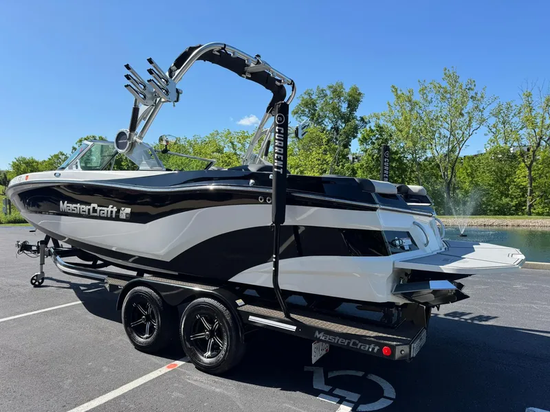 Slide: The Image of 2020 MasterCraft XT22 boat on trailer, parked outdoors, with trees in the background. - 4