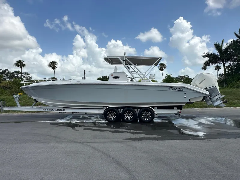 Slide: The Image of 2006 Dakota 36 Cuddy boat on trailer, parked outdoors under a partly cloudy sky. - 3