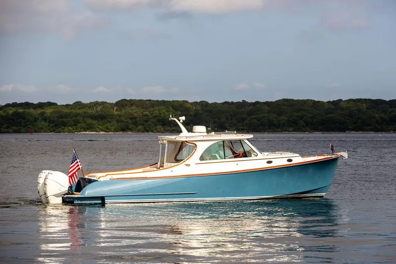 Slide: The Image of 2022 Hinckley 35 boat on calm water with American flag, scenic background. - 1