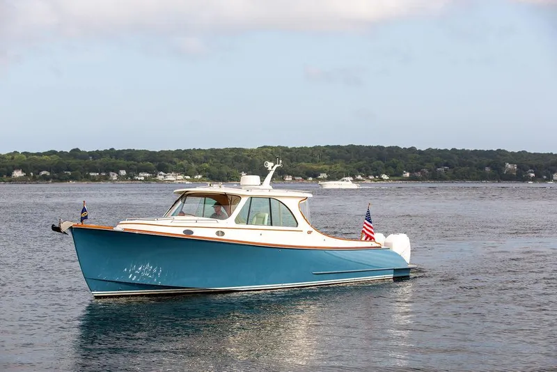 Slide: The Image of 2022 Hinckley 35 boat cruising on a calm lake with scenic shoreline. - 4