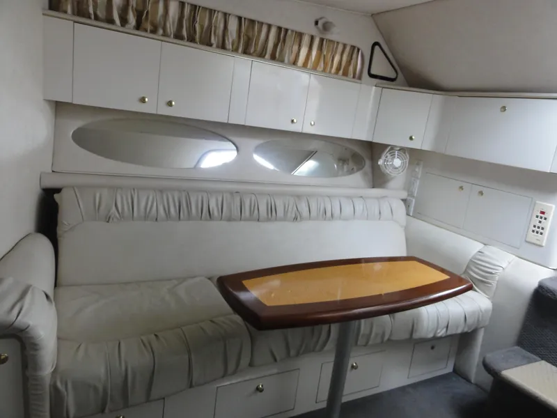 Slide: The Image of Interior of 1997 Sea Ray 330 Express, featuring a cozy seating area with a wooden table. - 27