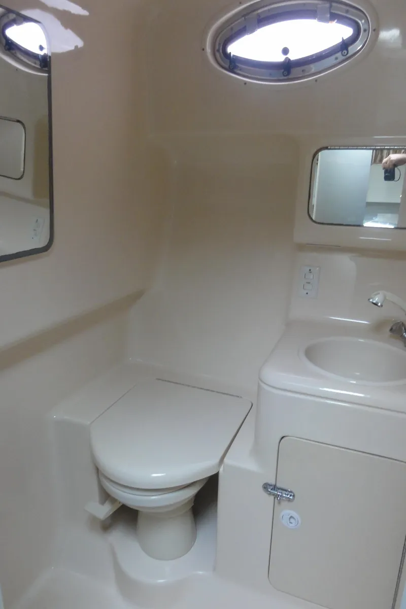 Slide: The Image of 1997 Sea Ray 330 Express bathroom with toilet, sink, and porthole window. - 28