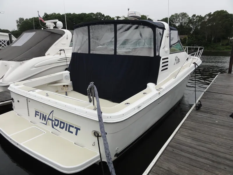 Slide: The Image of 1997 Sea Ray 330 Express boat docked, named "Fin Addict," with covered cockpit. - 4