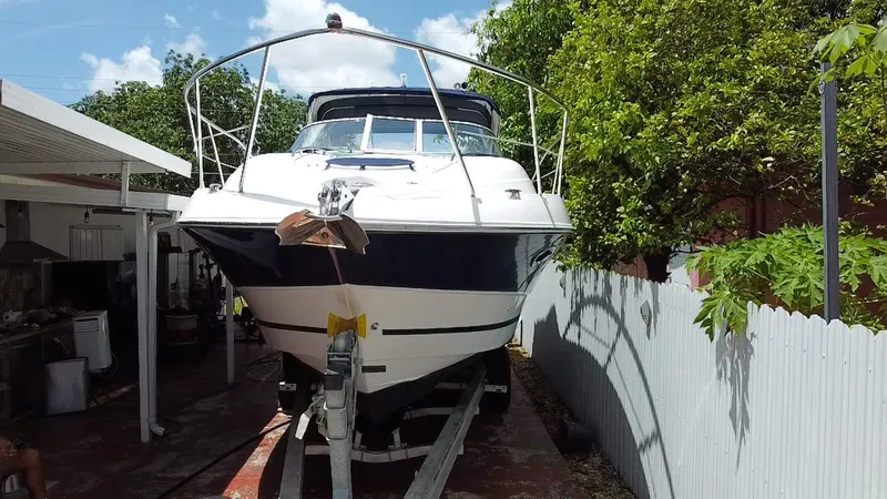 Slide: The Image of 2006 Doral 310 Intrigue boat on trailer, surrounded by trees and a fence. - 11