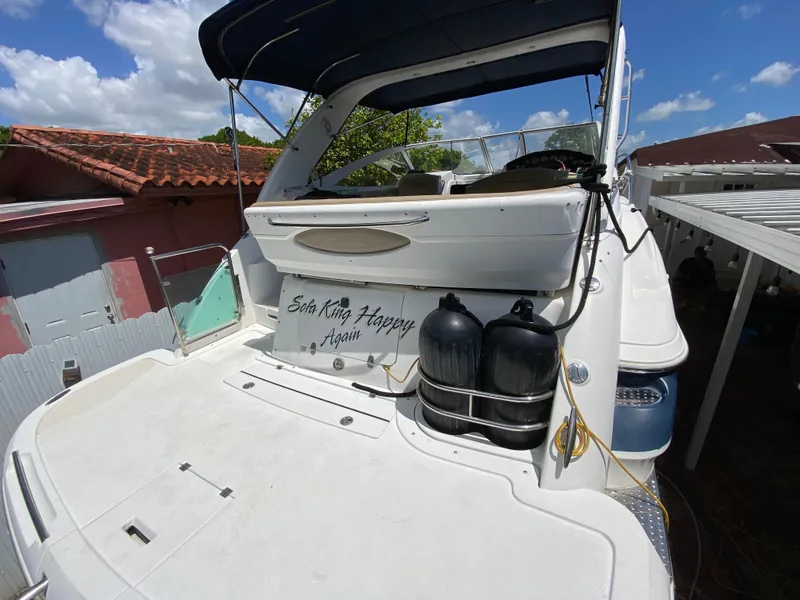 Slide: The Image of 2006 Doral 310 Intrigue boat docked, featuring spacious deck and protective canopy. - 14