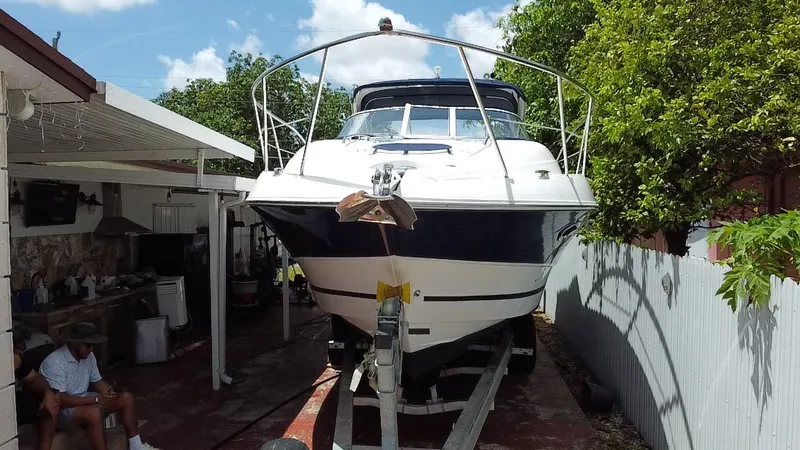 Slide: The Image of 2006 Doral 310 Intrigue boat on trailer, parked beside a house with trees. - 7