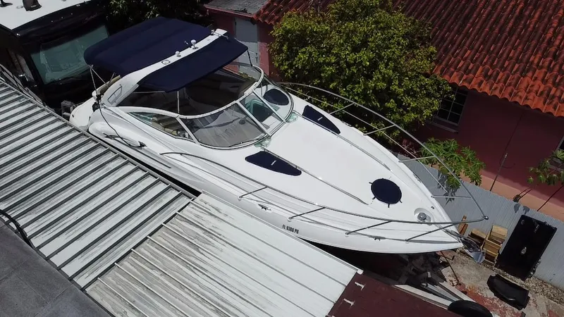 Slide: The Image of 2006 Doral 310 Intrigue boat docked near buildings with red roof and greenery. - 8