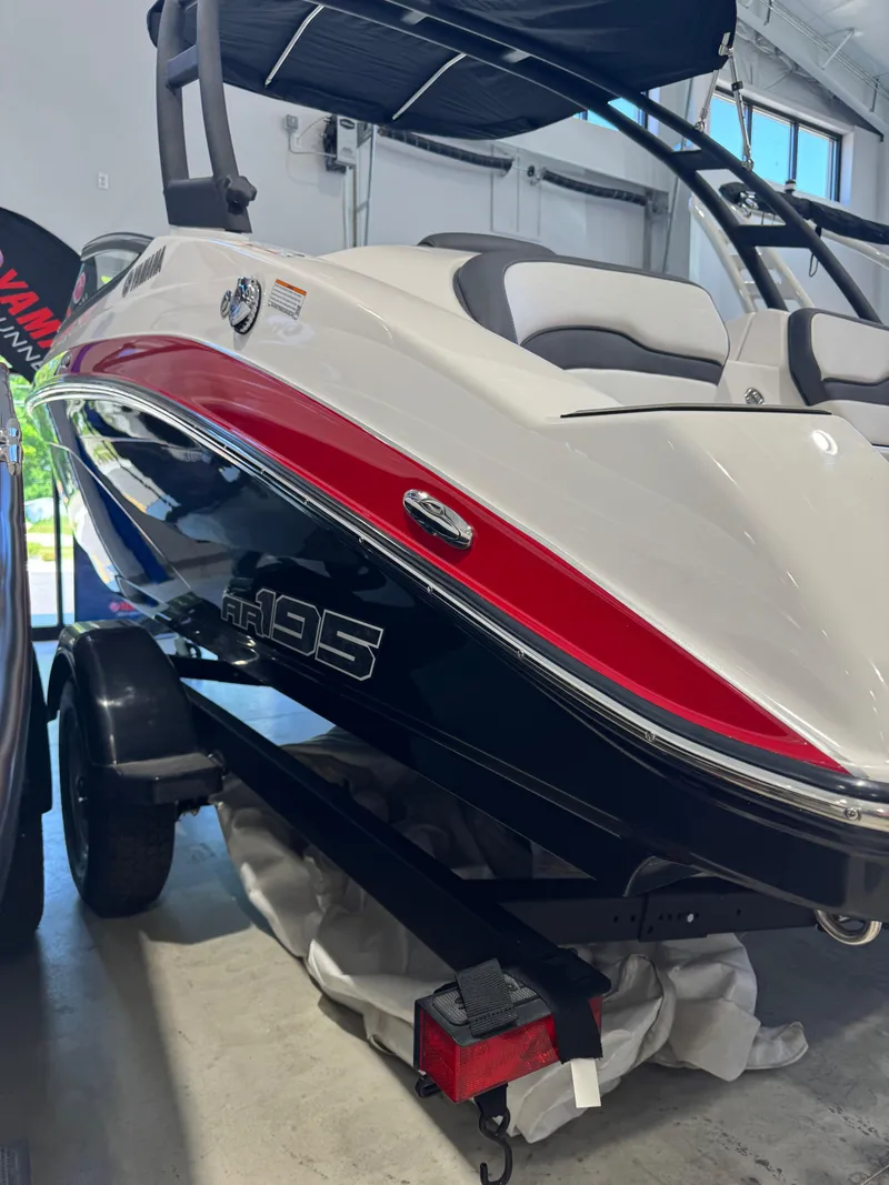 Slide: The Image of 2025 Yamaha Boats AR195 in showroom, featuring sleek design and vibrant red accents. - 1