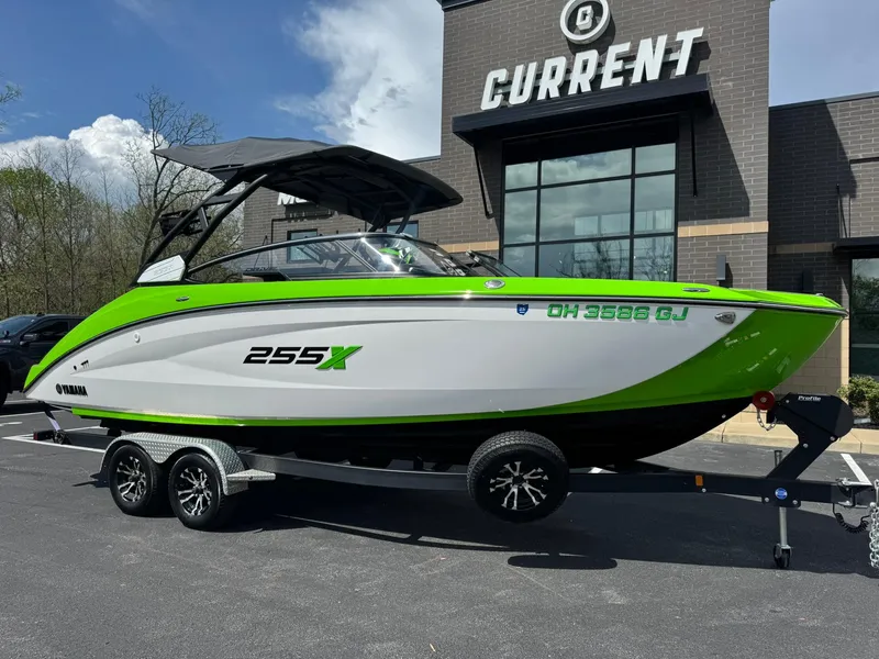 Slide: The Image of 2022 Yamaha Boats 255XD in green and white, parked on a trailer outside a building. - 1