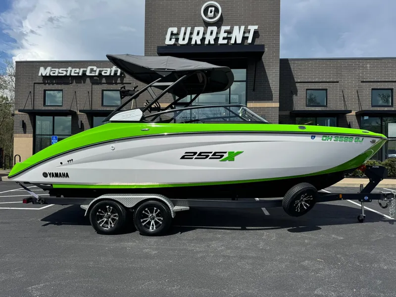 Slide: The Image of 2022 Yamaha Boats 255XD in vibrant green and white, parked outside a dealership. - 2