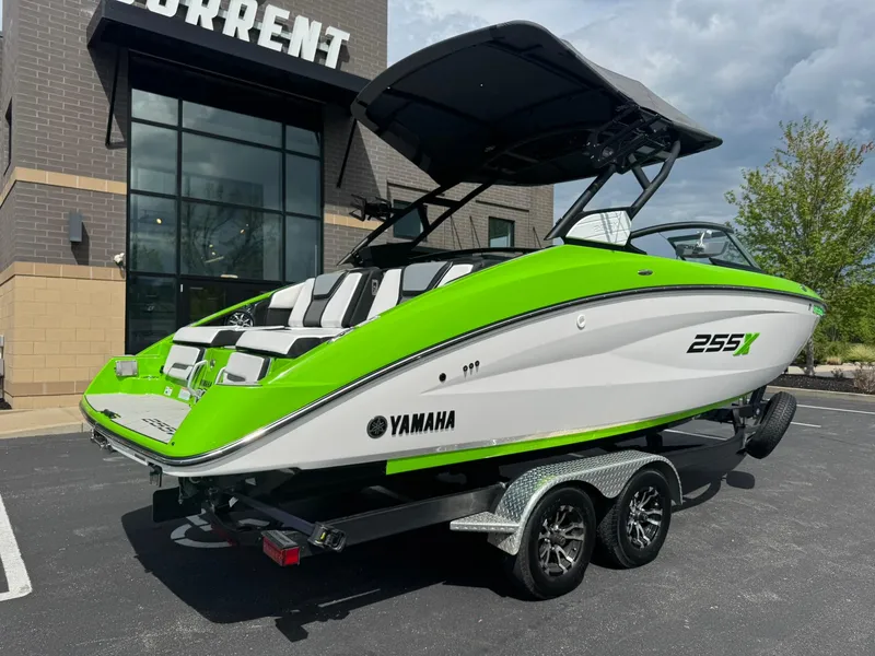 Slide: The Image of 2022 Yamaha Boats 255XD in vibrant green, parked on a trailer outside a building. - 22