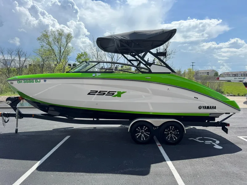 Slide: The Image of 2022 Yamaha Boats 255XD in parking lot, green and white design, under a cloudy sky. - 6