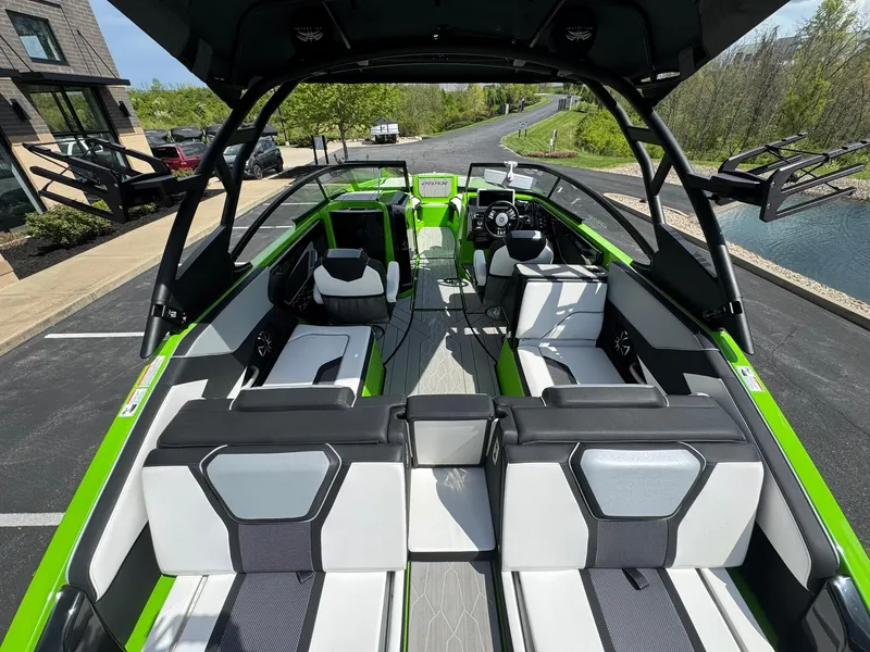 Slide: The Image of 2022 Yamaha Boats 255XD with sleek green and white interior, docked near a scenic road. - 8