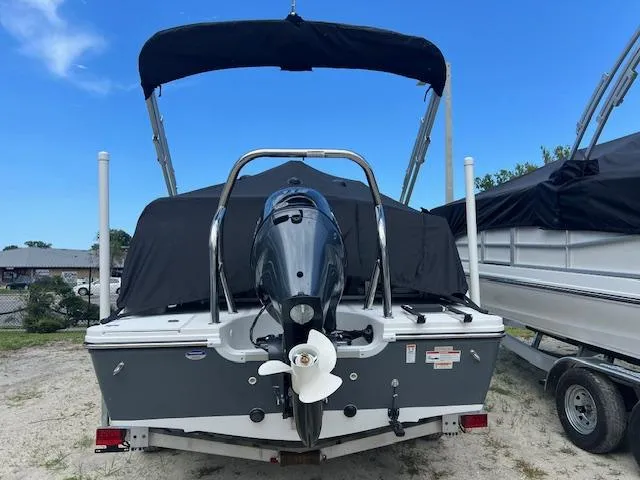 Slide: The Image of 2025 Hurricane FunDeck 1960 RE OB boat with outboard motor and canopy, parked on sandy ground. - 1