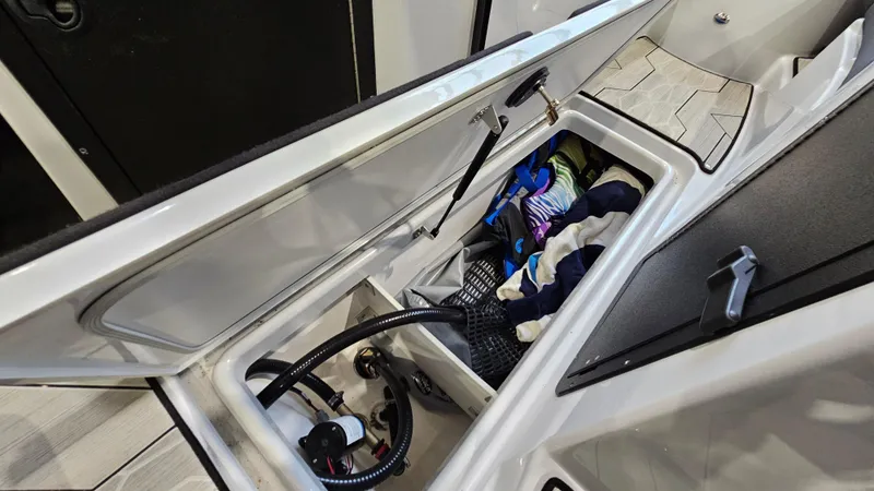 Slide: The Image of 2023 Yamaha Boats 222XD storage compartment with gear and equipment. - 24