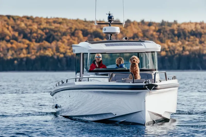 Slide: The Image of 2025 Axopar 37XC CROSS CABIN on water with passengers and a dog. - 13