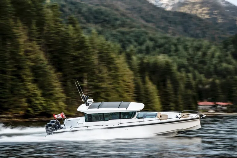 Slide: The Image of 2025 Axopar 37XC CROSS CABIN cruising on a scenic forest-lined waterway. - 6