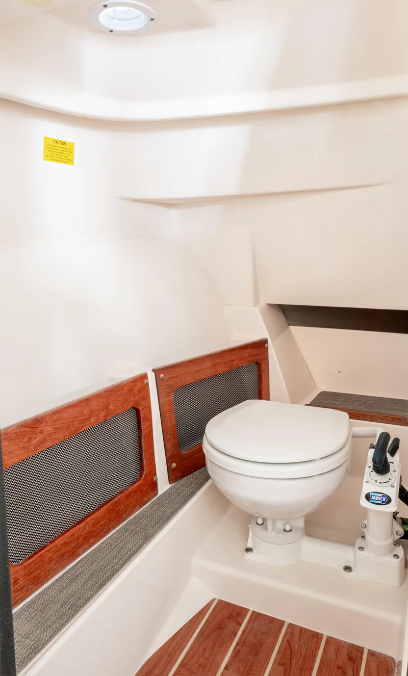 Slide: The Image of 2025 Grady-White 235 Freedom boat interior with toilet and wood accents. - 10
