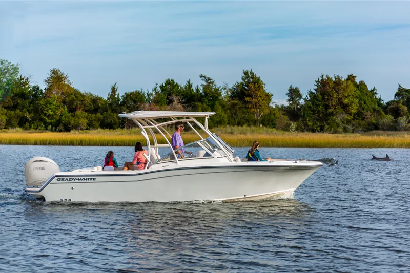 Slide: The Image of 2025 Grady-White 235 Freedom boat cruising on a scenic lake with passengers onboard. - 2