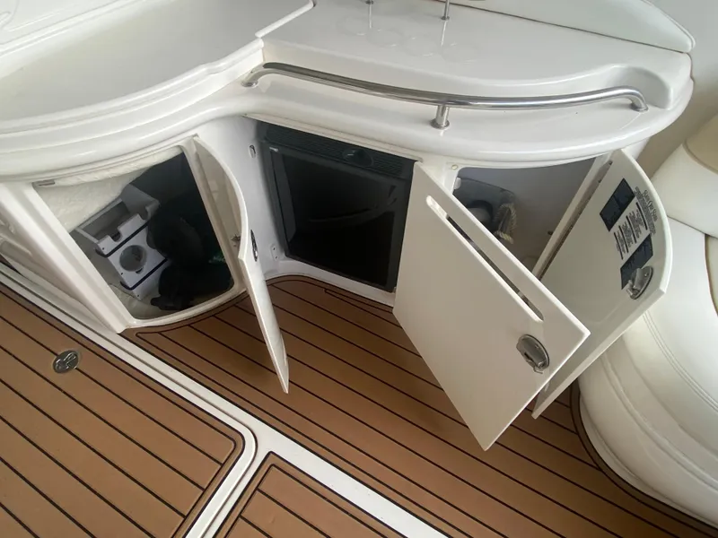 Slide: The Image of 2003 Sea Ray 290 Bowrider interior with open storage compartments and teak flooring. - 16