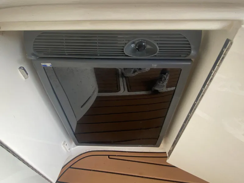 Slide: The Image of 2003 Sea Ray 290 Bowrider interior with a built-in refrigerator and wooden flooring. - 17