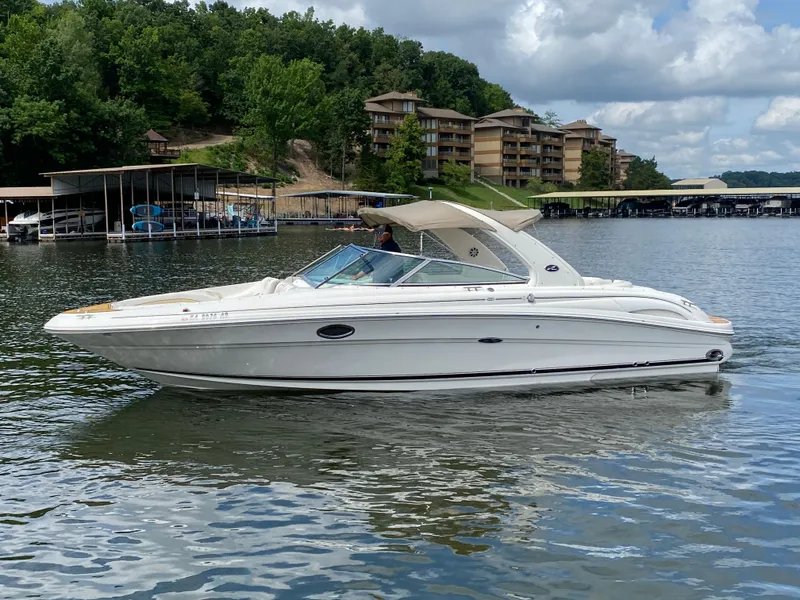 Slide: The Image of 2003 Sea Ray 290 Bowrider on a lake, surrounded by trees and buildings. - 2