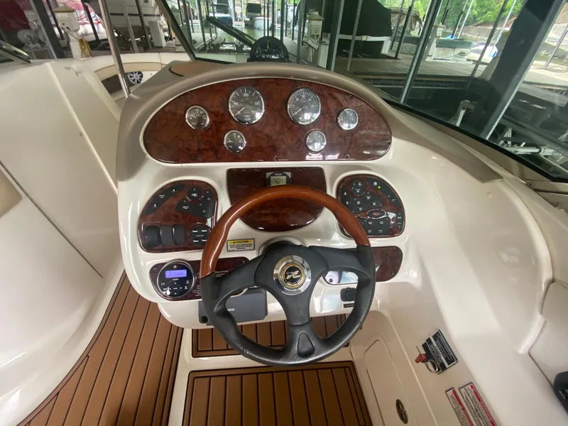 Slide: The Image of 2003 Sea Ray 290 Bowrider dashboard with wood accents and steering wheel. - 22