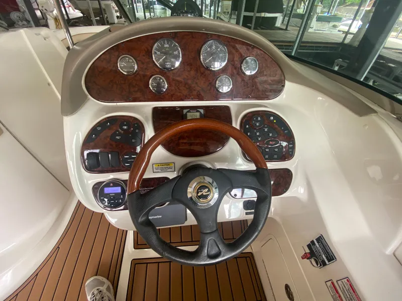 Slide: The Image of 2003 Sea Ray 290 Bowrider dashboard with wood accents and steering wheel. - 25