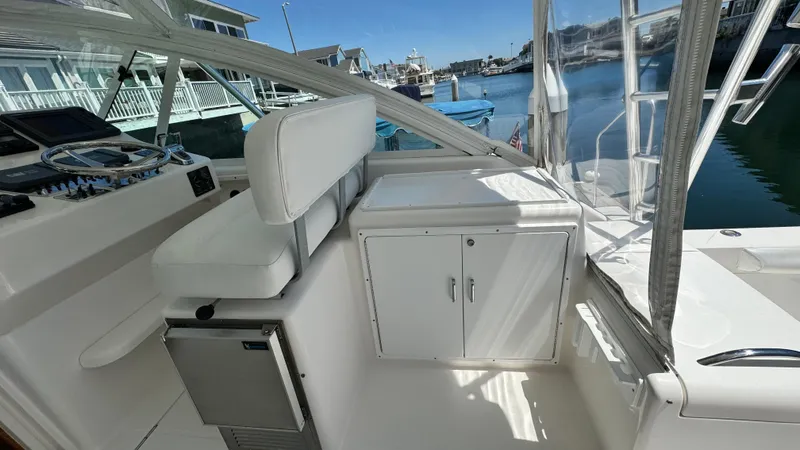 Slide: The Image of 2005 Cabo 35 Express boat interior with seating, storage, and marina view. - 10