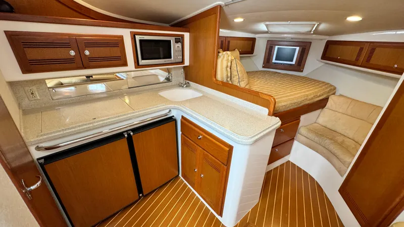 Slide: The Image of 2005 Cabo 35 Express interior with kitchenette, bed, and seating area. - 11