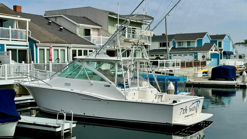 Slide: The Image of 2005 Cabo 35 Express boat docked in a marina, surrounded by colorful waterfront homes. - 14