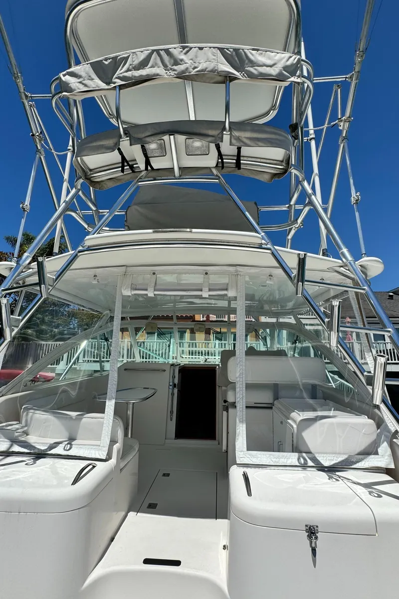 Slide: The Image of 2005 Cabo 35 Express boat with tower, white exterior, docked under clear blue sky. - 9