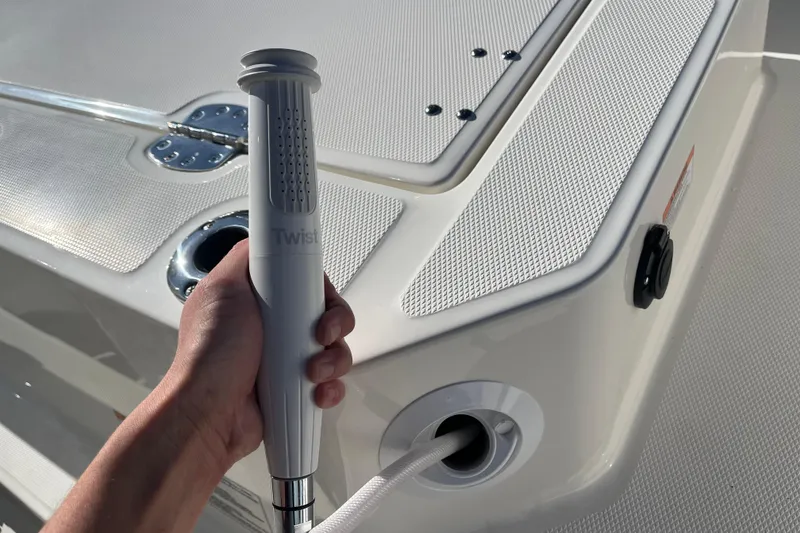 Slide: The Image of Hand holding a shower handle on a 2026 Boston Whaler 280 Dauntless boat deck. - 27