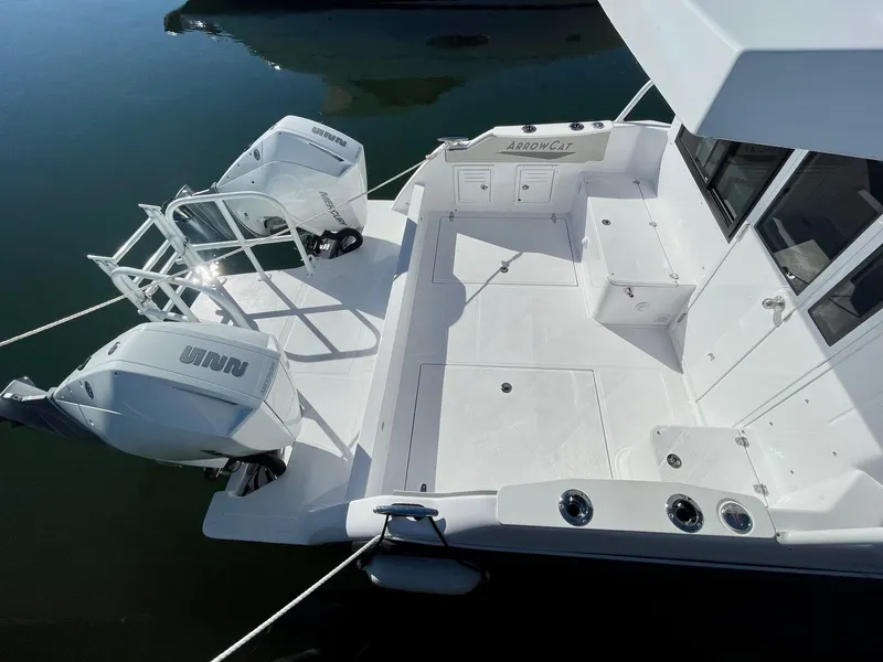 Slide: The Image of 2025 ArrowCat 320 boat deck with dual outboard motors, docked on calm water. - 2