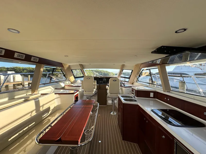 Slide: The Image of Interior of 2025 ArrowCat 420 Coupe yacht with modern kitchen and helm, docked by water. - 3