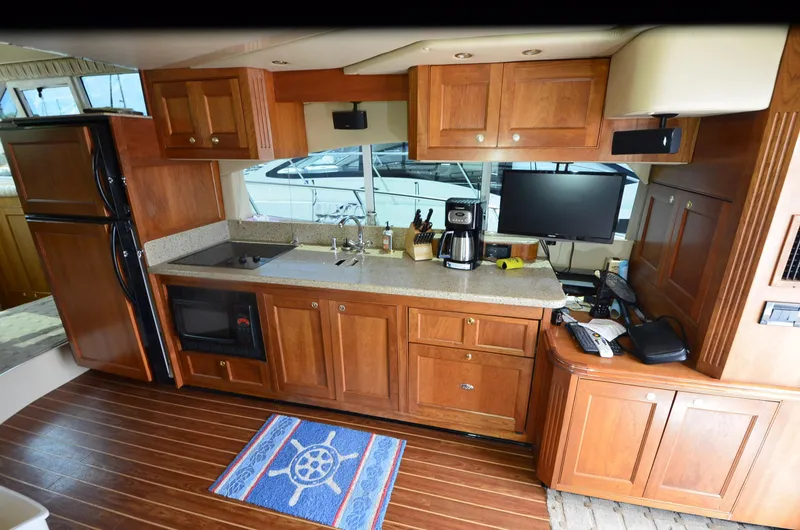 Slide: The Image of 2003 Cruisers Yachts 5000 Sedan Sport kitchen with wooden cabinets and modern appliances. - 37