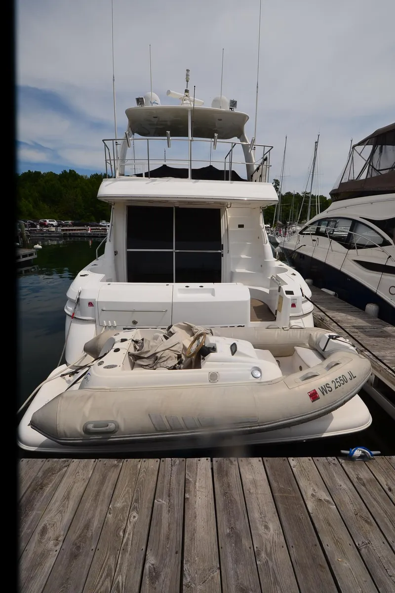 Slide: The Image of 2003 Cruisers Yachts 5000 Sedan Sport docked with inflatable boat at marina. - 7