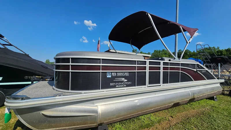 The Image of 2020 Bennington SX 23 Premium Swingback pontoon boat with canopy, parked on grass under blue sky. - 1