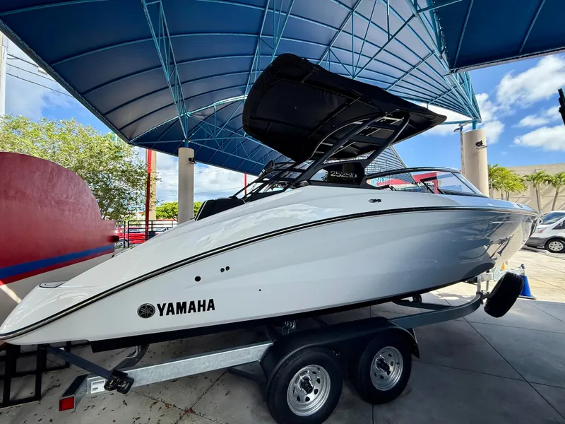 The Image of 2025 Yamaha Boats 252SD on trailer under blue canopy. - 1