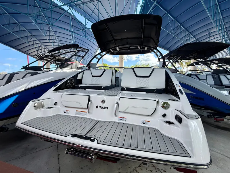 Slide: The Image of 2025 Yamaha Boats 252SD, sleek design, under a blue canopy, rear view. - 2